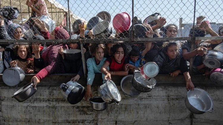 Desplazados palestinos hacen cola para recibir comida