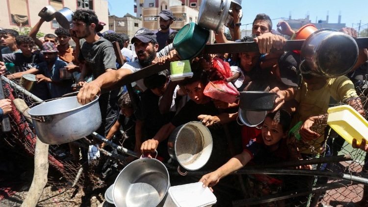 Palestinos recibiendo alimentos de una cocina de caridad, en medio de una crisis de hambre, en Nuseirat.